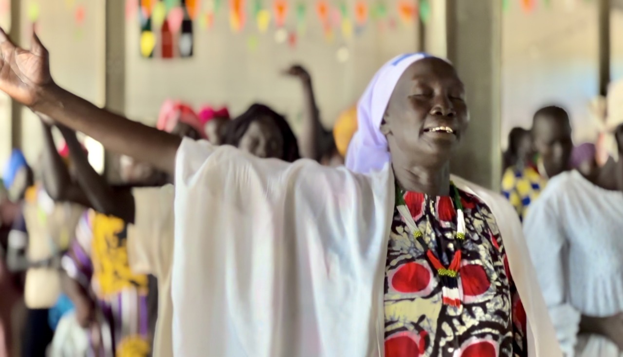 A woman raising her right hand while praying.