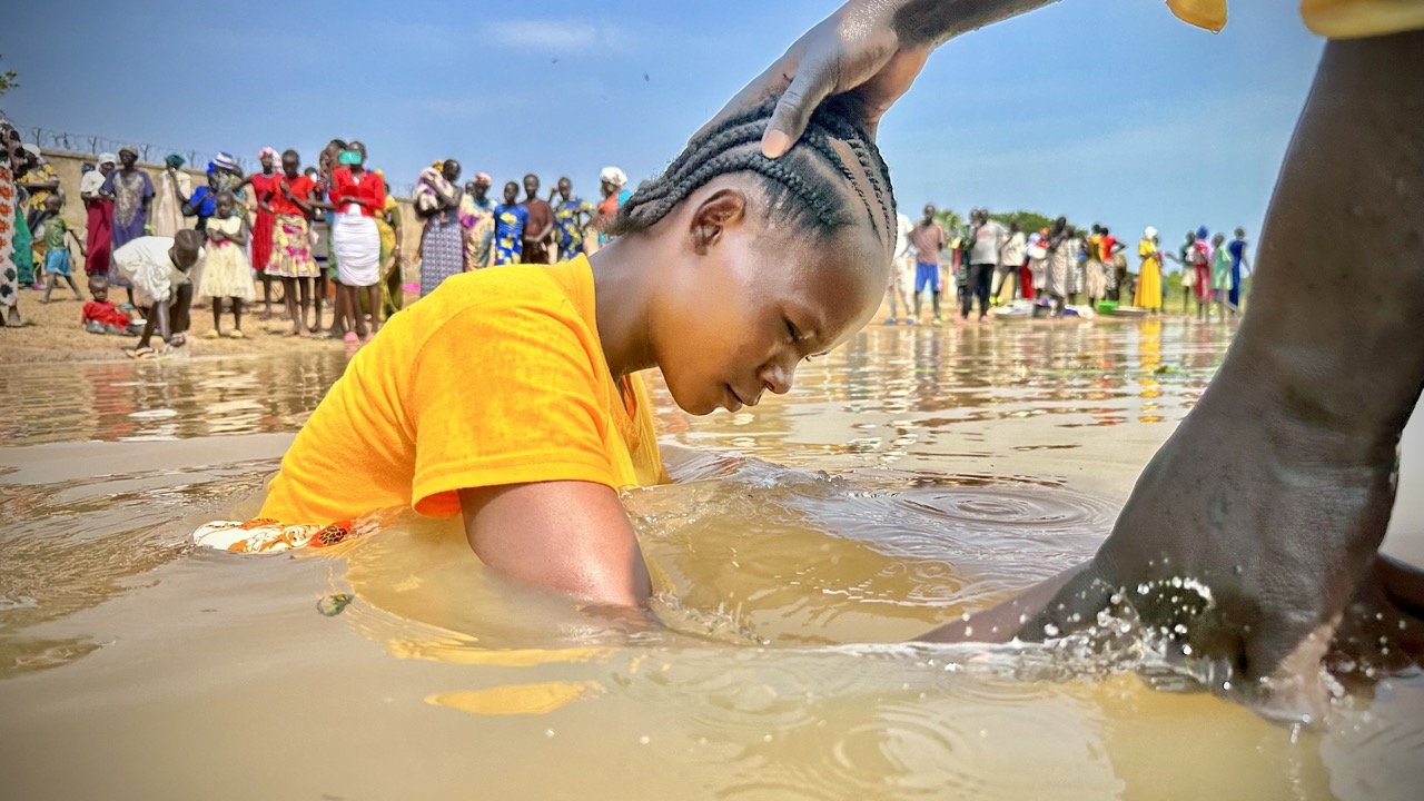 A child getting baptism in the South Sudan river.