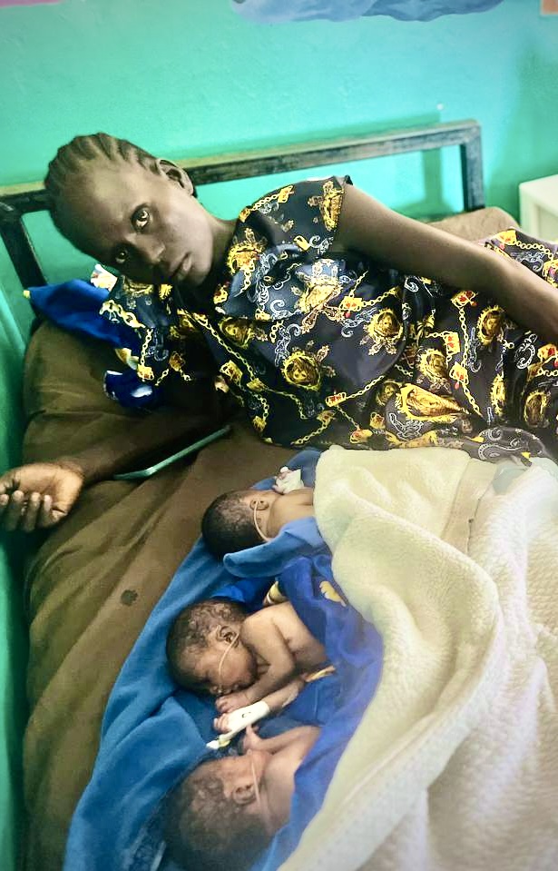 A person lying on a bed with three babies