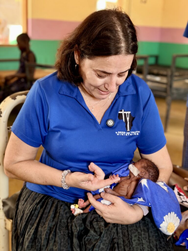 Suzy prays for a baby on the neonatal ward A person holding a baby